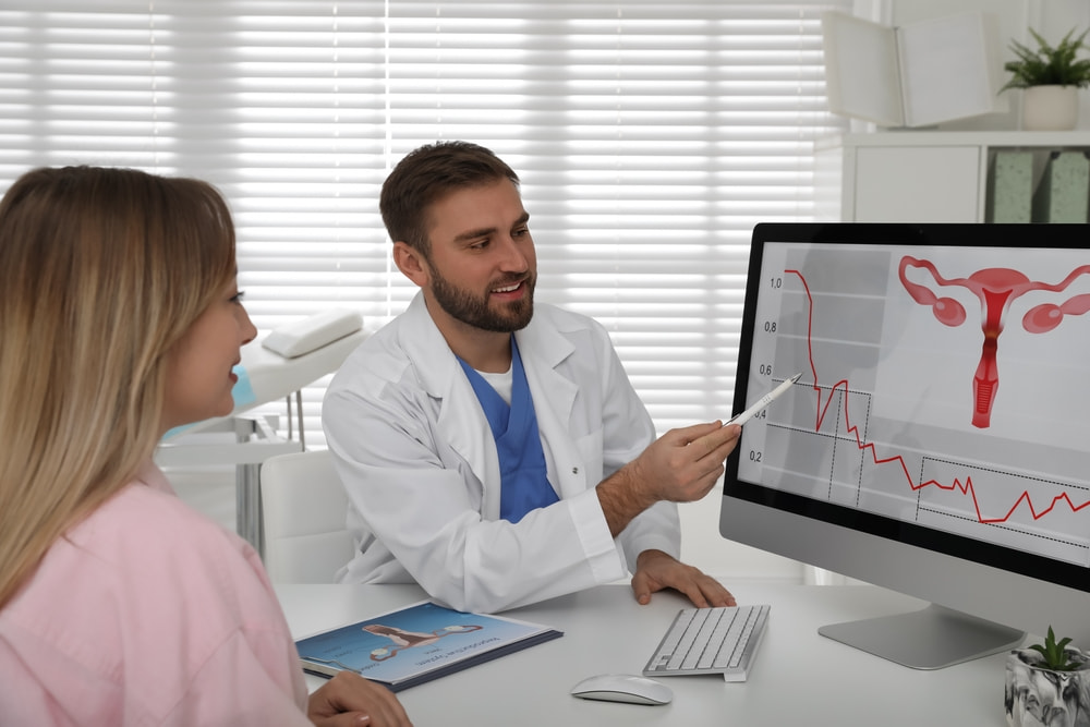 Médico ginecologista mostrando a tela do computador para paciente mulher